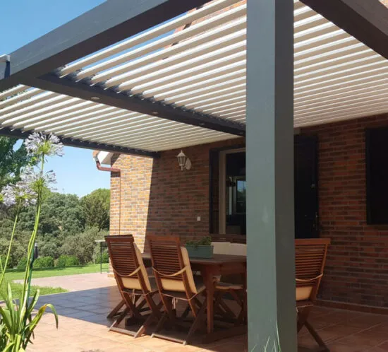Modern aluminium pergola with adjustable louvres providing shade for an outdoor dining area